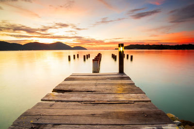 Pier over lake against sky during sunset