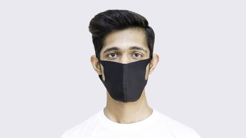 Portrait of man covering face against white background