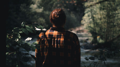 Rear view of woman standing by plants in forest