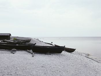 Boat moored on beach against sky