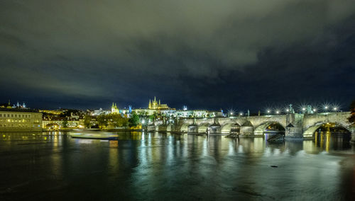 Illuminated bridge over river against sky at night