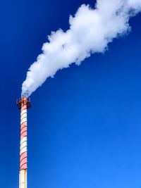 Low angle view of smoke stacks against blue sky