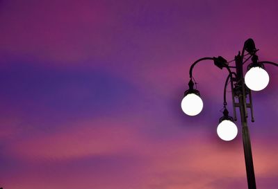 Low angle view of illuminated street light against sky