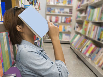 Side view of woman with book in library