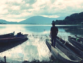 Rear view of man standing on lake against sky