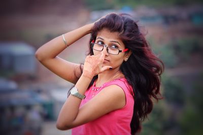 Side view of young woman wearing eyeglasses looking away while standing outdoors