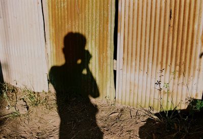 Shadow of man photographing corrugated iron fence