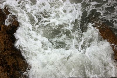 High angle view of waves breaking on rocks at shore