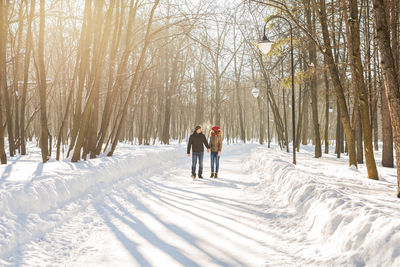 Rear view of people walking on snow covered land