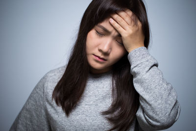 Young woman with headache against gray background