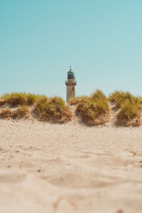 Lighthouse at beach against clear sky