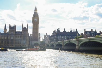 Arch bridge over river and buildings against sky