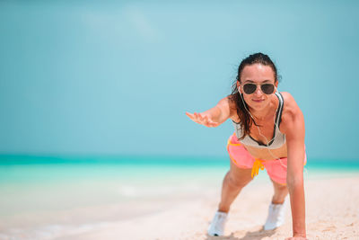 Young woman wearing sunglasses on beach against sky