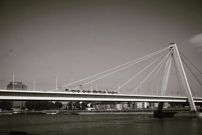 Bridge over river against sky in city