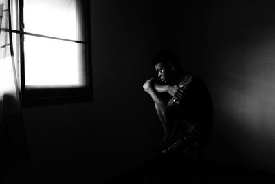 Portrait of young man sitting in window