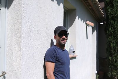 Portrait of young man standing against building