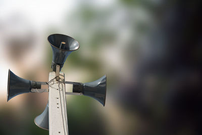 Low angle view of megaphones on metallic tower against blurred background