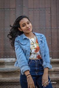 Portrait of beautiful young woman standing against wall