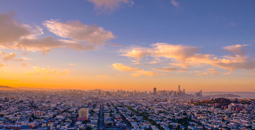 Aerial view of cityscape against cloudy sky during sunset