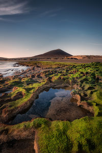 Scenic view of land against sky during sunset