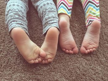 Low section of kids lying on rug at home