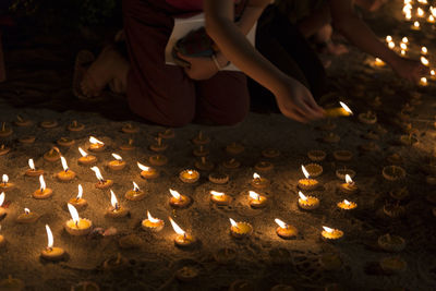 High angle view of hands lighting candles on land