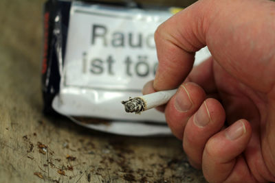 Close-up of hand smoking cigarette at table