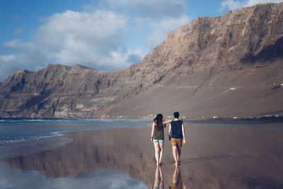 Rear view of a couple with mountain against sky