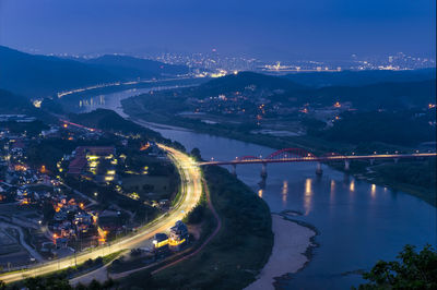 High angle view of illuminated bridge over river amidst buildings in city