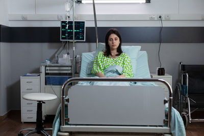 Stressed patient sitting on bed in hospital