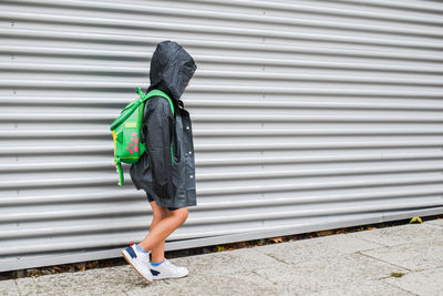 Side view of boy walking against shutter