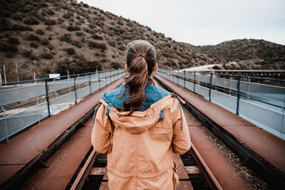 Rear view of woman on railroad tracks against sky