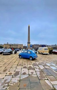 Cars on city street against blue sky