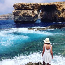 Rear view of woman looking at rock formation in sea