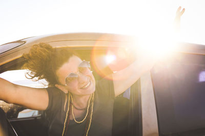 Portrait of cheerful woman wearing sunglasses in car