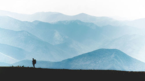 One woman in the mountain ridge with backpack with blue colours