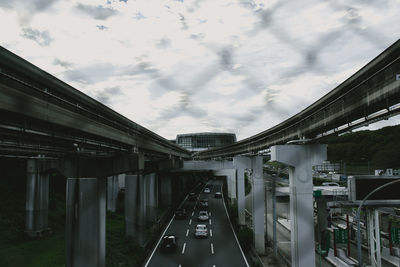 Road amidst bridges against cloudy sky