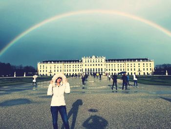 People standing in front of rainbow over city