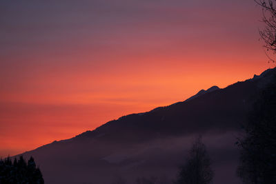 Scenic view of silhouette mountains against orange sky