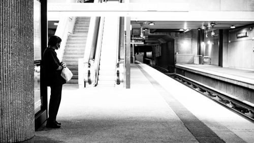 Side view of woman standing at railroad station