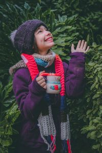 Young woman wearing hat while standing against plants