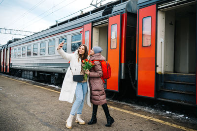 Girls with flowers on the station platform take a farewell selfie