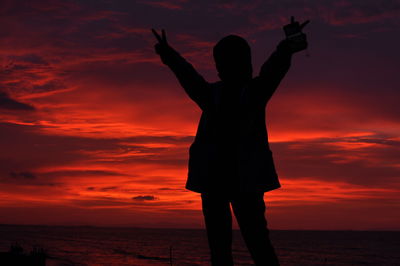 Silhouette woman standing at beach during sunset