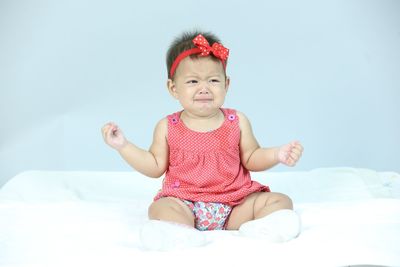 Portrait of smiling girl sitting on bed against sky