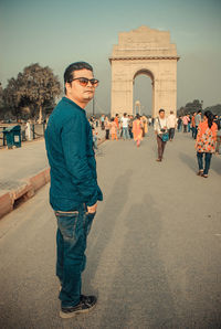 Full length of a young man standing in front of historical building