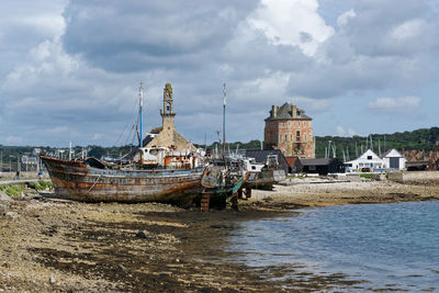 Fishing boats moored on beach against sky