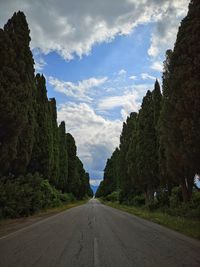 Empty road amidst trees against sky