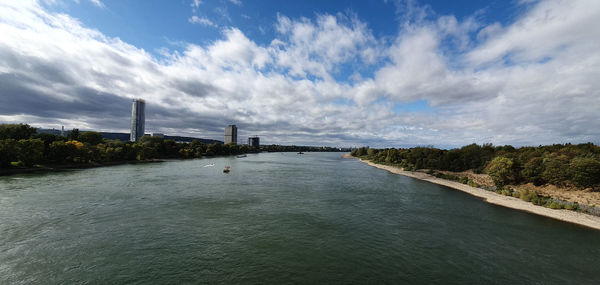 Scenic view of river by city against sky