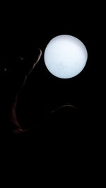 Person holding illuminated lighting equipment against black background