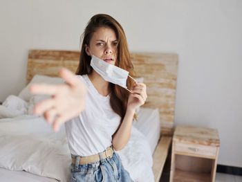 Portrait of a young woman sitting on bed at home